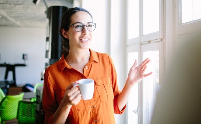 Kvinna-haller-kaffekopp-kontor