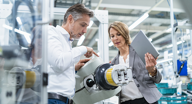 Man och kvinna inspekterar en maskin
