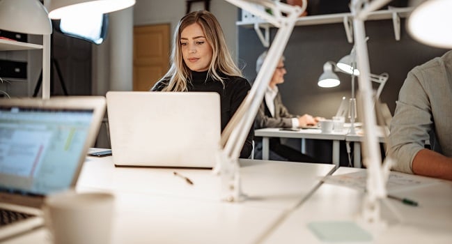 Kvinna i kontorsmiljö tittar på en laptop