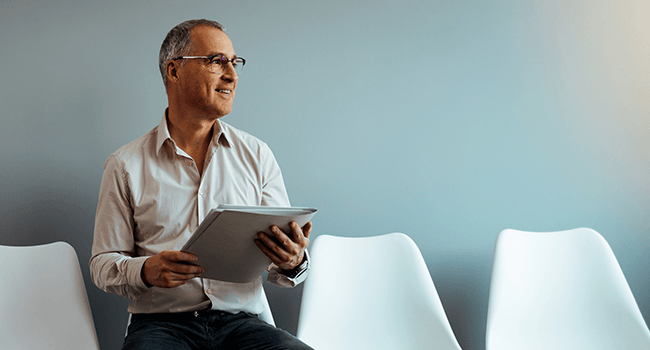 Man sitter på en stol och håller i en mapp