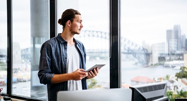 Man på kontor ser ut genom fönster