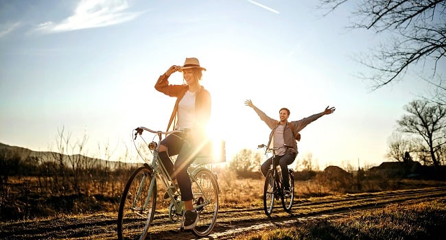 Kvinna man cyklar på landsväg sommar
