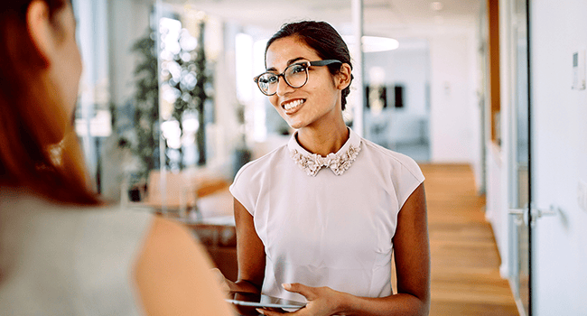 Kvinna med ipad talar med kollega