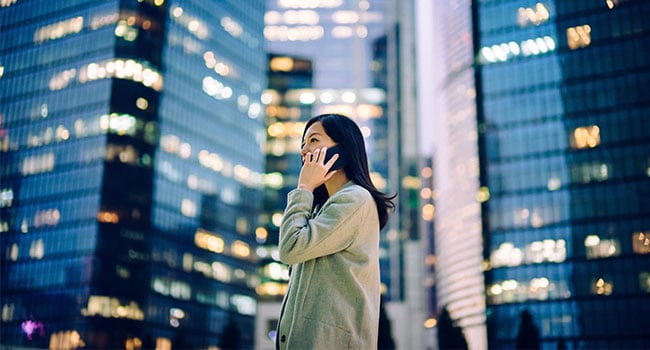 Kvinna med mobiltelefon vid skyskrapa 